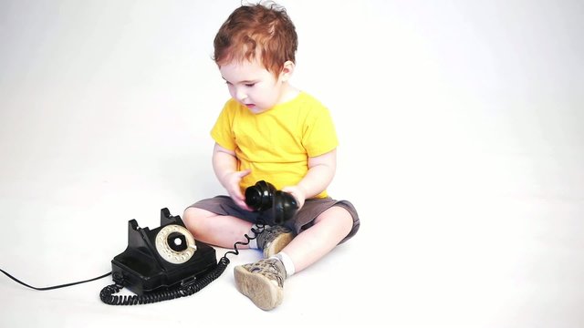 a kid playing with an old telephone