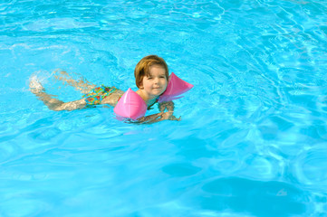 Fototapeta na wymiar Toddler girl learning to swim in the swimming pool