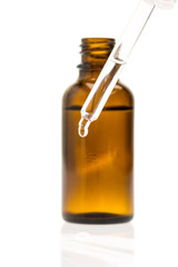 Pipette mit Tropfen vor einer Flasche