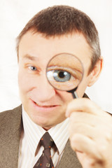 Fototapeta na wymiar Angry man looks through a magnifying glass