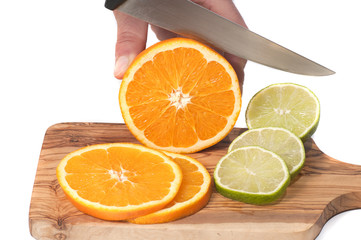 hand cutting orange and lime slices on a wooden board