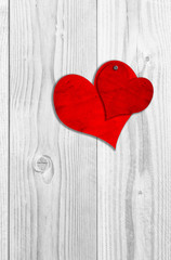 Conceptual two red old paper vintage hearts nailed on white wood