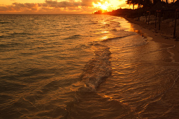 golden caribbean sunrise with wave and beach
