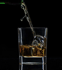 Pouring whiskey into glass, isolated on black background