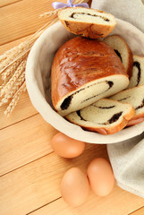 Loaf with poppy seeds in wicker basket, on wooden background