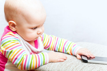 Little baby in casual colorful striped clothing with phone