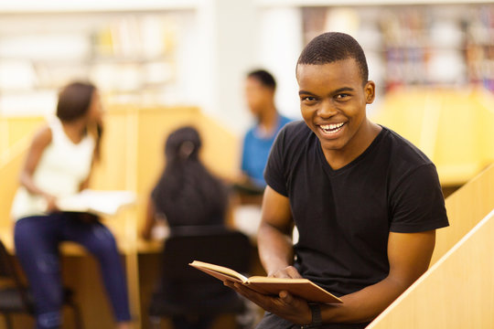 happy male african college student reading book in library