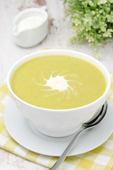 bowl of green pea soup with ginger and cream, vertical