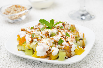 fruit salad with nuts, yogurt and mint garnished with yogurt