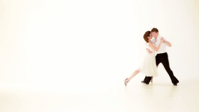 passionate, young couple showing dance moves on white background