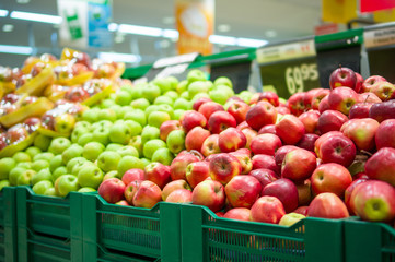 Bunch of red and green apples on boxes in supermarket