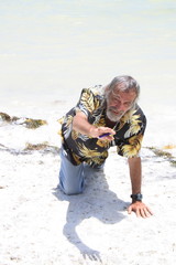 Men on his knees on the sand by the sea