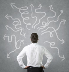 Confused businessman looking at many twisted arrows