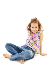 Pretty little girl sitting on the floor in jeans