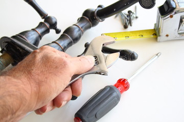 Plumber hand with tools changing a bathroom water faucet