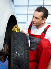 Car mechanic checks the tread pattern of a winter tire