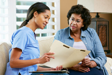 Nurse Discussing Records With Senior Female Patient at Home