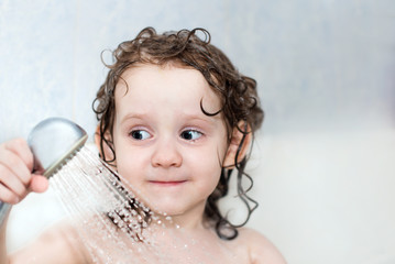 little girl in the bathroom holding a shower