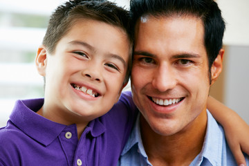 Portrait Of Father And Son Sitting On Sofa At Home