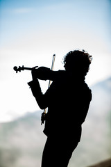 violinist silhouetted on volcano