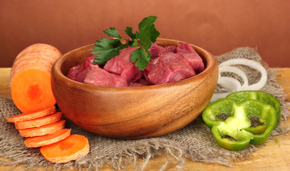 Raw beef meat in bowl with vegetables