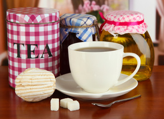 Jar and cup of tea on table in room