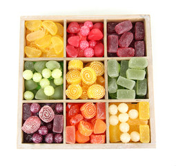 Multicolor candies in wooden box, isolated on white