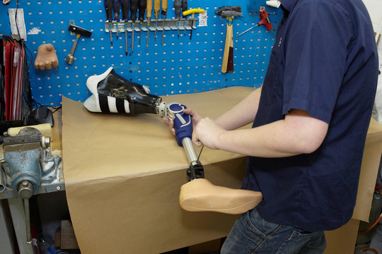 A technician adjusts a prosthetic foot.