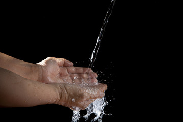 hand and pouring water on black background
