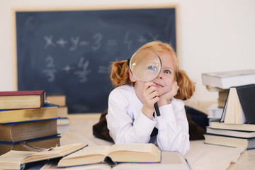 girl lies with a magnifying glass and books