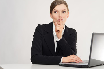 Woman with laptop whispering, with secret in the office