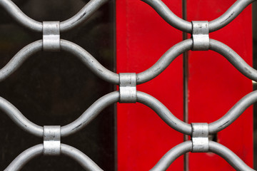 Grille de sécurité métallique sur fond rouge et noir