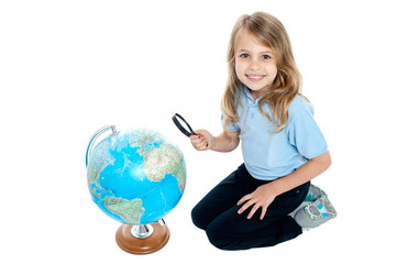 Girl watching globe through magnifying glass