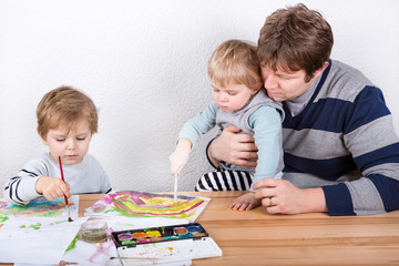 Father and two little boys siblings having fun painting