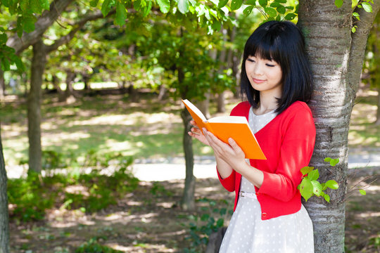atractive asian woman reading a book in the park