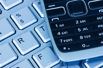 Obraz premium Phone on keyboard in blue tint