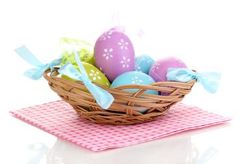 Colorful easter eggs in basket on napkin isolated on white