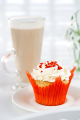 red festive muffin and coffe Latte in a glass, on white wooden t