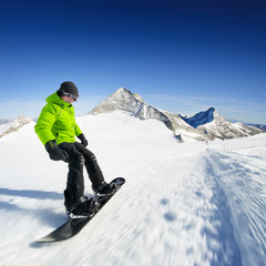 Snowboarder on piste in high mountains