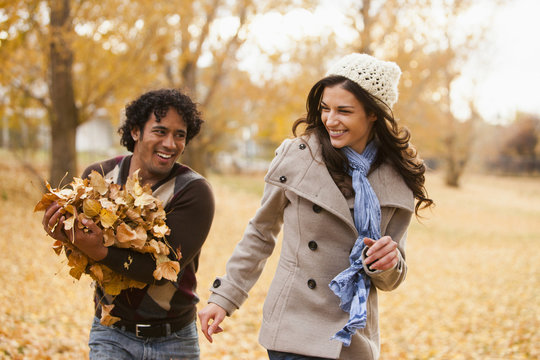 Couple playing in autumn leaves