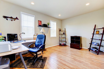 Home office with hardwood floor and simple furniture.