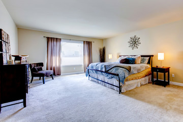 Large bedroom with beige carpet and black bed.