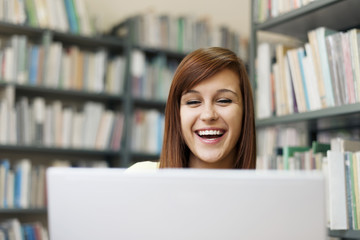 Happy student using laptop in library