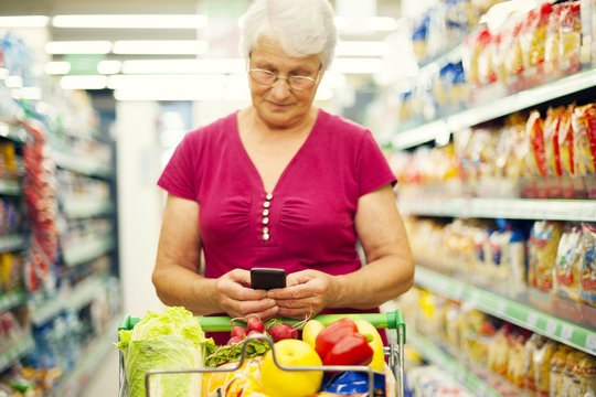 Senior woman texting on mobile phone at supermarket