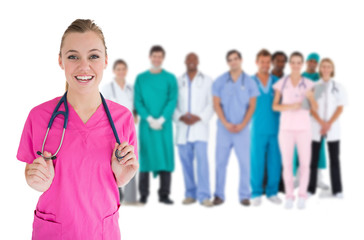 Smiling nurse with medical staff behind her