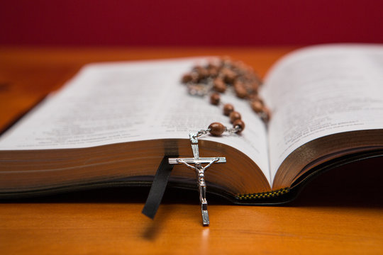 Rosary beads resting on open bible - Powered by Adobe