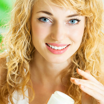 Happy smiling woman applying creme, indoor