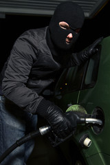 masked man using gas pump