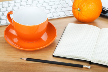 Coffee cup, orange fruit and office supplies