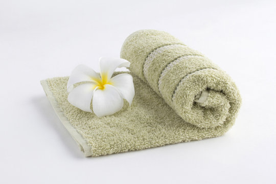 A green towel rolled up with flower on a white background